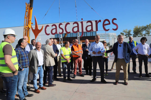 Responsables y trabajadores de Cascajares y de las empresas constructoras junto al cartel de Cascajares que sobrevivi&oacute; al incendio y que se ha vuelto a recolocar en las nuevas instalaciones. / Br&aacute;gimo (ICAL)