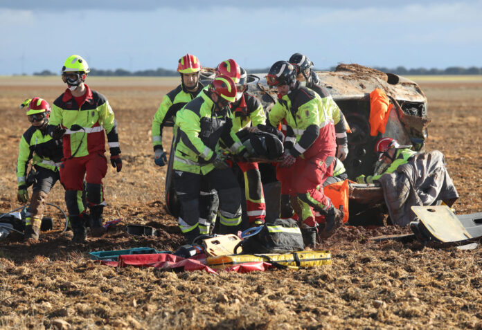 Dos personas heridas tras en el vuelco de su vehículo en la carretera P-901 a la altura de Paredes de Monte (Palencia) Bomberos de la capital (traje rojo y amarillo) y voluntarios de los parques de la Diputación (traje negro y amarillo) rescatan a una de las heridas en un accidente. / Brágimo (ICAL)