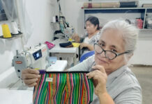 Un mujer peruana muestra unos de los bolsos elaborados en un taller de Paita, región de Piura de Perú y que se comercializan en la tienda Vida propia de Guardo (Palencia)
