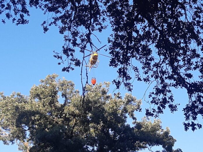 Un helicóptero se encamina a cargar en las piscinas del Monte. / Óscar Herrero